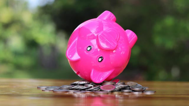 Piggy bank upside down on the pile of coins isolated on the table. 