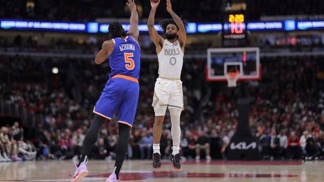 Chicago Bulls guard Coby White (0) shoots a 3-point basket over New York Knicks forward Precious Achiuwa (5) during the second half of an NBA basketball game, Saturday, Jan. 4, 2025, in Chicago. 