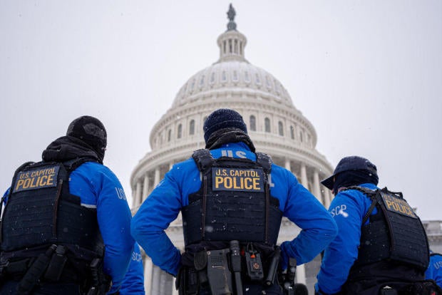 The dome of the U.S. Capitol Building is visible as U.S. Capitol Police officers stand guard in a winter storm in the nation's capital on Jan. 6, 2025. 