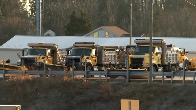 Three dumptrucks are lined up to treat the roads ahead of Monday's snow 