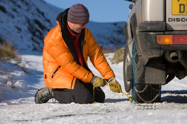 Caucasian Male (45) attaching snow chains to vehicle 