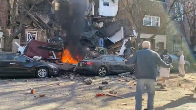 People watch as a fire burns after a home exploded in South Philadelphia 