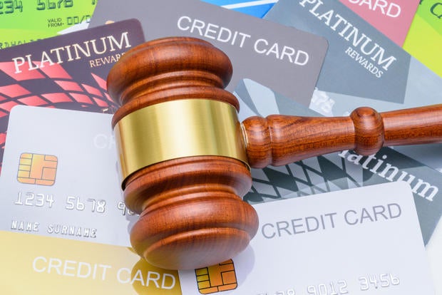 Legal proceedings in financial disputes, credit card debt settlement and financial regulation : A wooden gavel placed on top of many credit cards, depicting regulations surrounding credit and banking. 