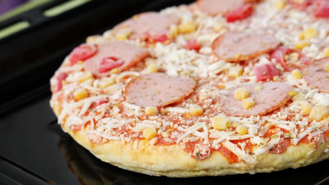 Frozen pizza with salami, cheese, corn and pepper 