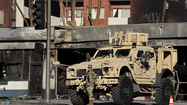 A member of the National Guard stands next to an armored vehicle in the wake of the Palisades Fire in the Pacific Palisades neighborhood in Los Angeles, Jan. 15, 2025. 