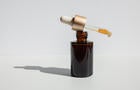 Brown glass with a dropper. Bottle mockup cosmetic oil dropper on a grey background and shadows. Copy space 