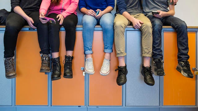 schoolchildren sitting on lockers 