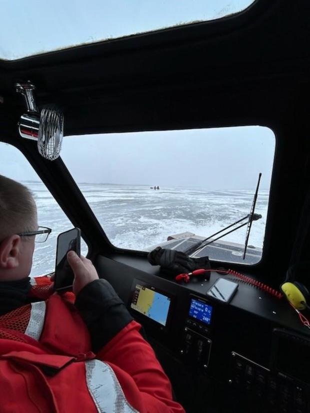 Coast Guard crews seen approaching two people on the ice. 