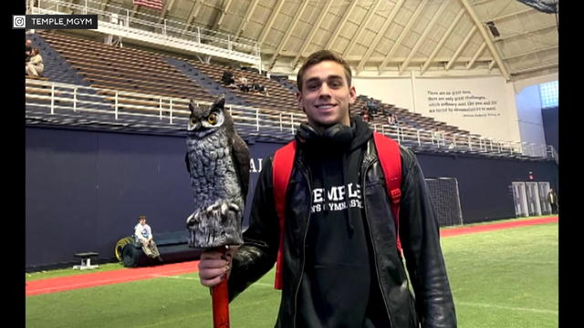 Tyler Sabapathy smiles for a photo, holding an owl doll in a gym 