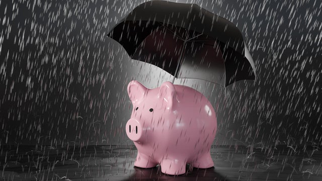 Pink piggy bank holding a black umbrella in heavy rain. Illustration of the concept of protection of savings and investment 