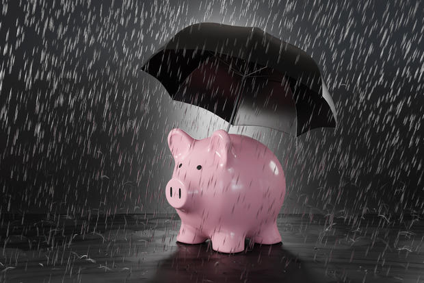 Pink piggy bank holding a black umbrella in heavy rain. Illustration of the concept of protection of savings and investment 