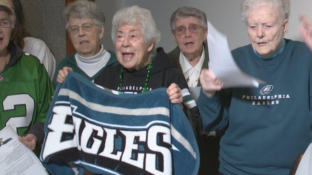 A group of women in Eagles gear is singing a song 