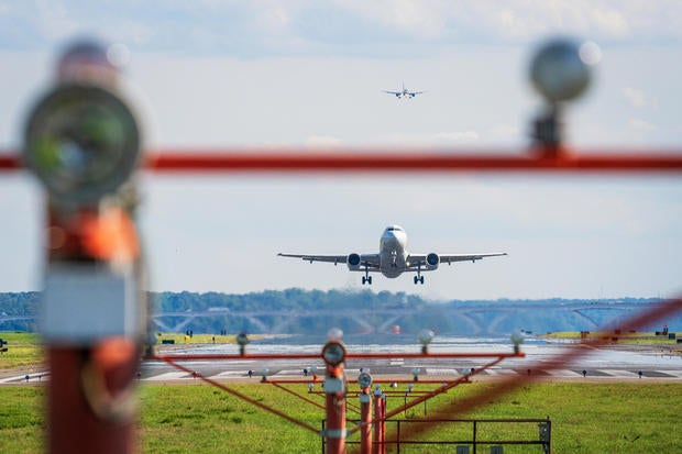 A passenger jet is framed in the runway threshold lights on takeoff as another jet lines up for landing in the background at Ronald Reagan Washington National Airport on Aug. 12, 2024, in Arlington, Virginia. 