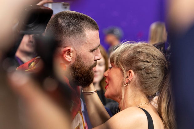 Travis Kelce and Taylor Swift look at each other as the Chief celebrate winning Super Bowl 2024 on the field