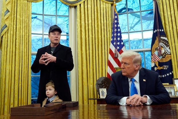 President Trump listens as Elon Musk, joined by his son, speaks in the Oval Office of the White House in Washington, D.C., on Tuesday, Feb. 11, 2025.