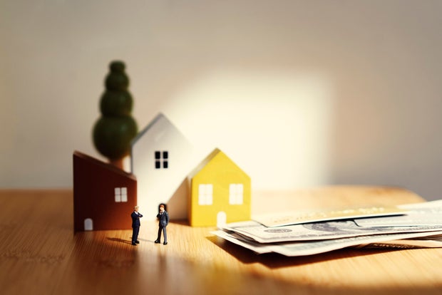 Wooden small people and small house on the bamboo table with copy space Home loan and family concept