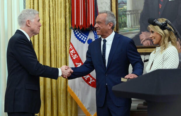 The new U.S. secretary of health and human services, Robert F. Kennedy Jr., shakes hands with Supreme Court Associate Justice Neil Gorsuch after being sworn in in the Oval Office at the White House in Washington, D.C., on Feb. 13, 2025. 