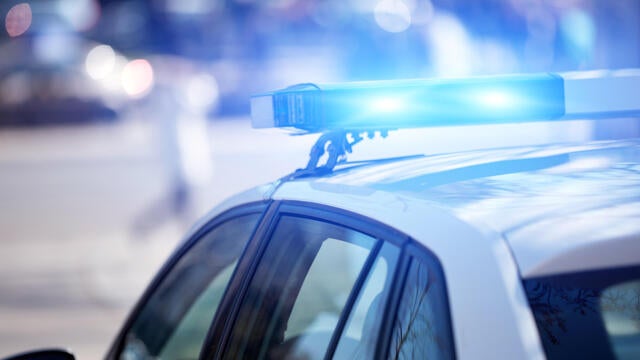 Police car with blue lights on the crime scene in traffic urban environment. 