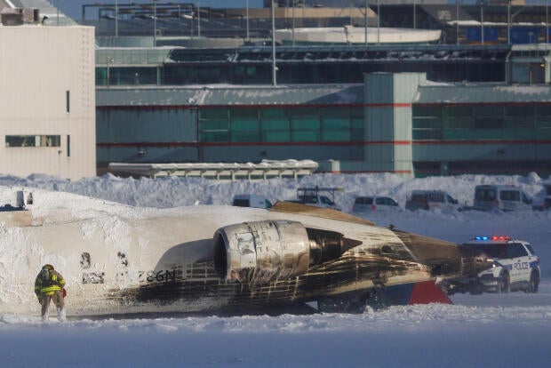 An emergency responder works around an aircraft on a runway, after a plane crash at Toronto Pearson International Airport in Mississauga 