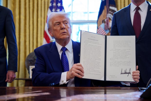 President Trump signs an executive order withholding federal funding from schools and universities that impose a COVID-19 vaccine mandate in the Oval Office at the White House on Feb. 14, 2025, in Washington, D.C.