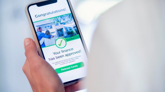 Woman holding a mobile phone with loan application approval. 