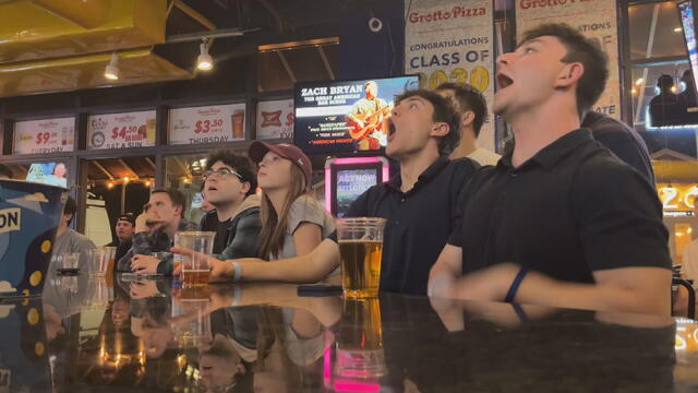 Students watch the basketball game at a bar 