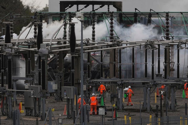 Workers are seen as smoke rising from the North Hyde Electric substation, which caught fire, resulting in the closure of Heathrow Airport in London on March 21, 2025.