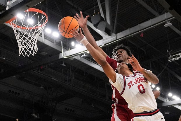 Arkansas forward Karter Knox, rear, reaches over St. John's guard Aaron Scott (0) to block a shot during the first half in the second round of the NCAA college basketball tournament, Saturday, March 22, 2025, in Providence, R.I.