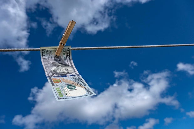 One hundred dollar bill drying on clothesline against sky 