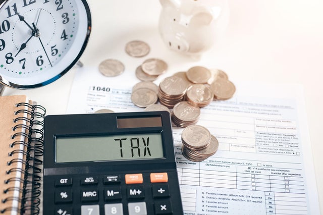 Tax word on a calculator. Business and tax concept. money and Form 1040 on the table.Annual tax payment 2021 