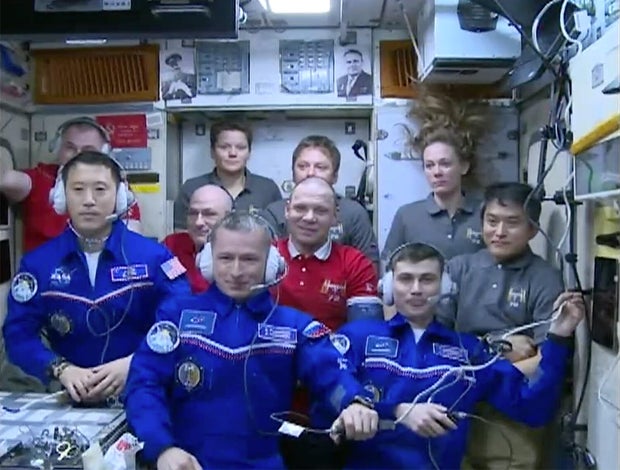Wearing dark blue flight suits, the Soyuz MS-27/73S crew -- from left, Jonny Kim, Sergey Ryzhikov and Alexey Zubritsky -- chats with flight controllers in a postdocking video call. They are replacing another Soyuz crew -- wearing red shirts from left, Alexey Ovchinin, NASA's Donald Pettit and cosmonaut Ivan Vagner -- who plan to depart April 19. The other four ISS crew members -- wearing dark green shirts from left, Anne McClain, cosmonaut Kirill Peskov, Nichole Ayers and Japanese astronaut Takuya Onishi -- flew to the station aboard a SpaceX Crew Dragon last month. 