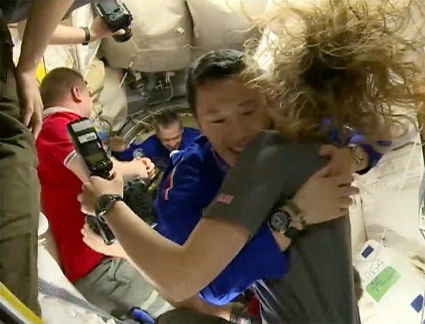 Floating into the space station, Jonny Kim hugs NASA astronaut Nichole Ayers amid smiles and handshakes and more hugs with the other six ISS crew members. 