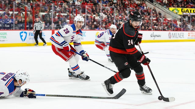 Seth Jarvis #24 of the Carolina Hurricanes skates with the puck past Braden Schneider #4 of the New York Rangers during the against the New York Rangers at Lenovo Center on April 12, 2025 in Raleigh, North Carolina.