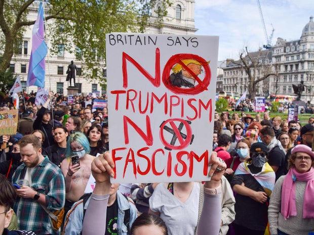 A protester holds a placard opposed to Trump and fascism 