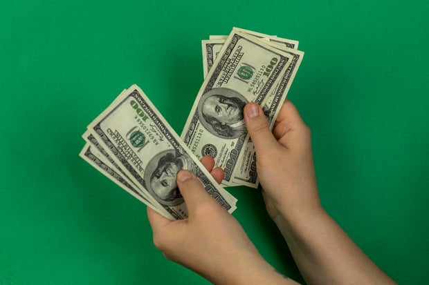 Hand holding hundreds of dollars green background 