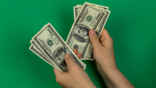 Hand holding hundreds of dollars green background 