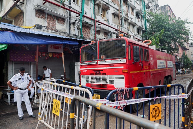 Police officers are at the guard near a fire truck outside a Charled hotel after a fire that killed several people in Kolkata