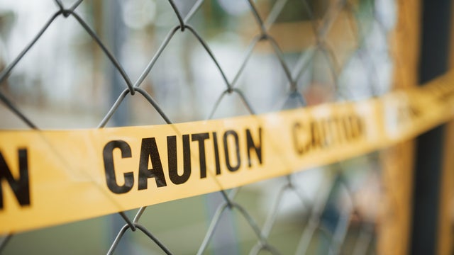 Do not enter. Yellow caution tape on the metal fence at daytime. Crime scene 
