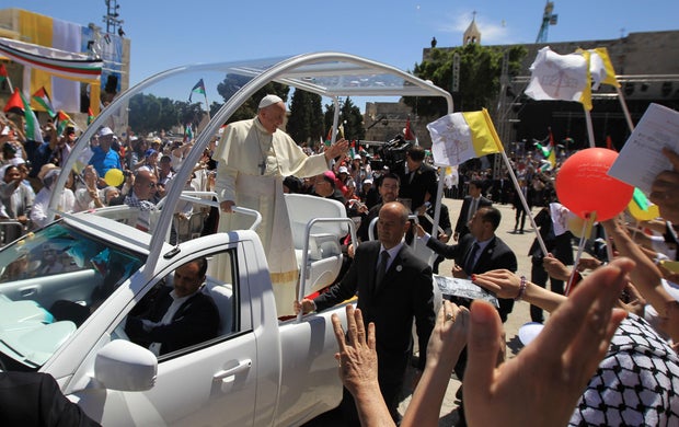 Pope Francis waves to the crowd from his popemobile as he arrives at Manger Square before presiding over an open-air Mass on May 25, 2014, outside the Church of the Nativity in the West Bank biblical town of Bethlehem.