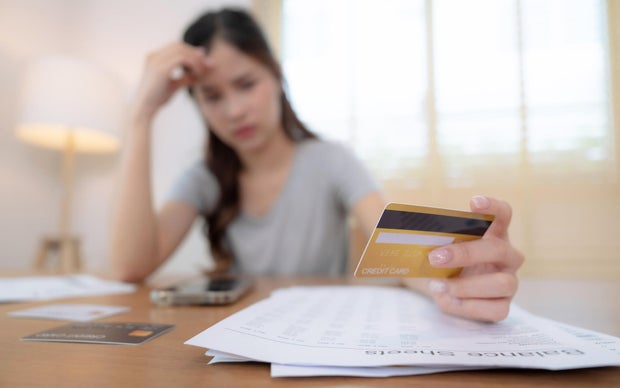 Stressed Asian woman seeing too high monthly expenses.