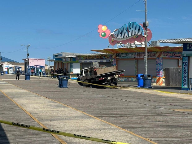 Wider shot of a truck partially fallen through the Wildwood boardwalk near Sugar Shack 