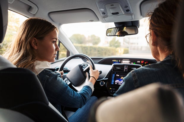 Teenage girl learning to drive from mother during weekend 