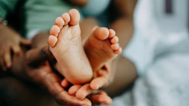 Mother's hand holds black baby's leg close-up 