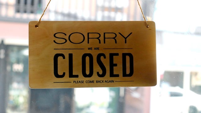 A sign that says Sorry we're closed hang on the door at a restaurant in this stock photo 