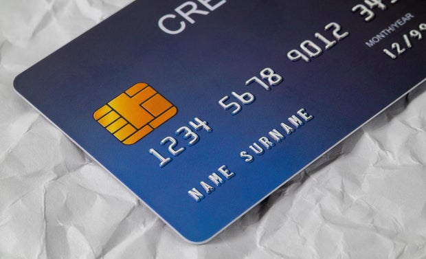 Close up of blue credit card placed on white paper. Online shopping payment and retail concept. Models and fake credit cards 