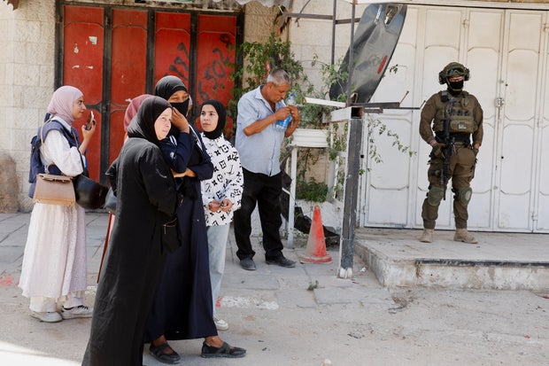 Palestinians stand as they are blocked by Israeli soldiers from entering the Tulkarm refugee camp to remove their belongings, in the Israeli-occupied West Bank, May 26, 2025.