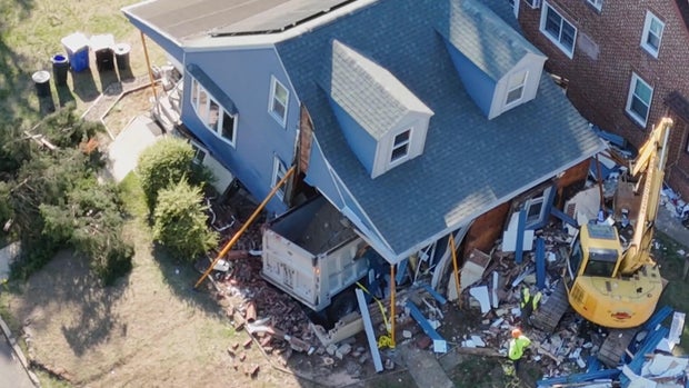 Overhead photo of the house after the dump truck crashed into it, a crane is on scene