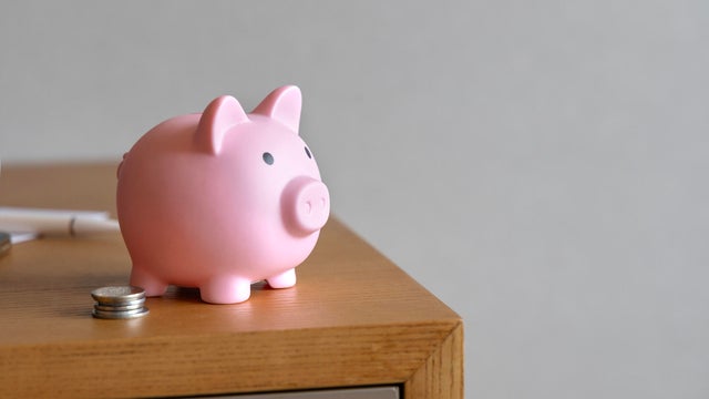 Piggy bank and coin stacks on wooden table top. 