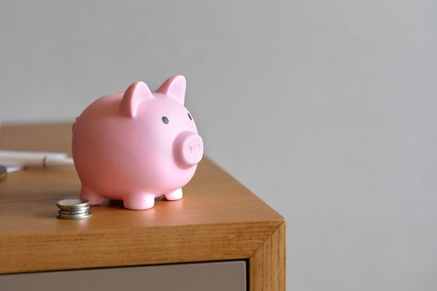 Piggy bank and coin stacks on wooden table top. 