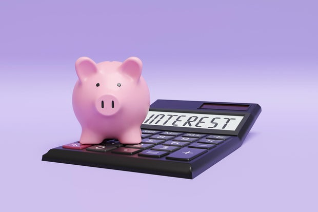 Pink piggy bank standing on a calculator on purple background. Illustration of the concept of interest rate of deposit savings 